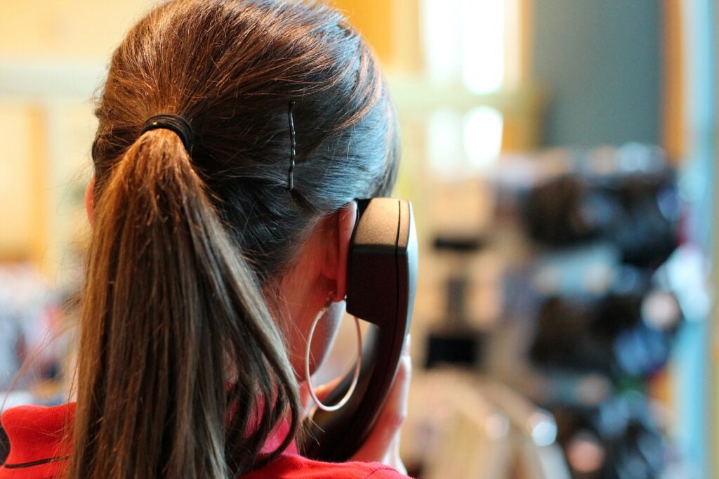 back of woman holding office phone to ear