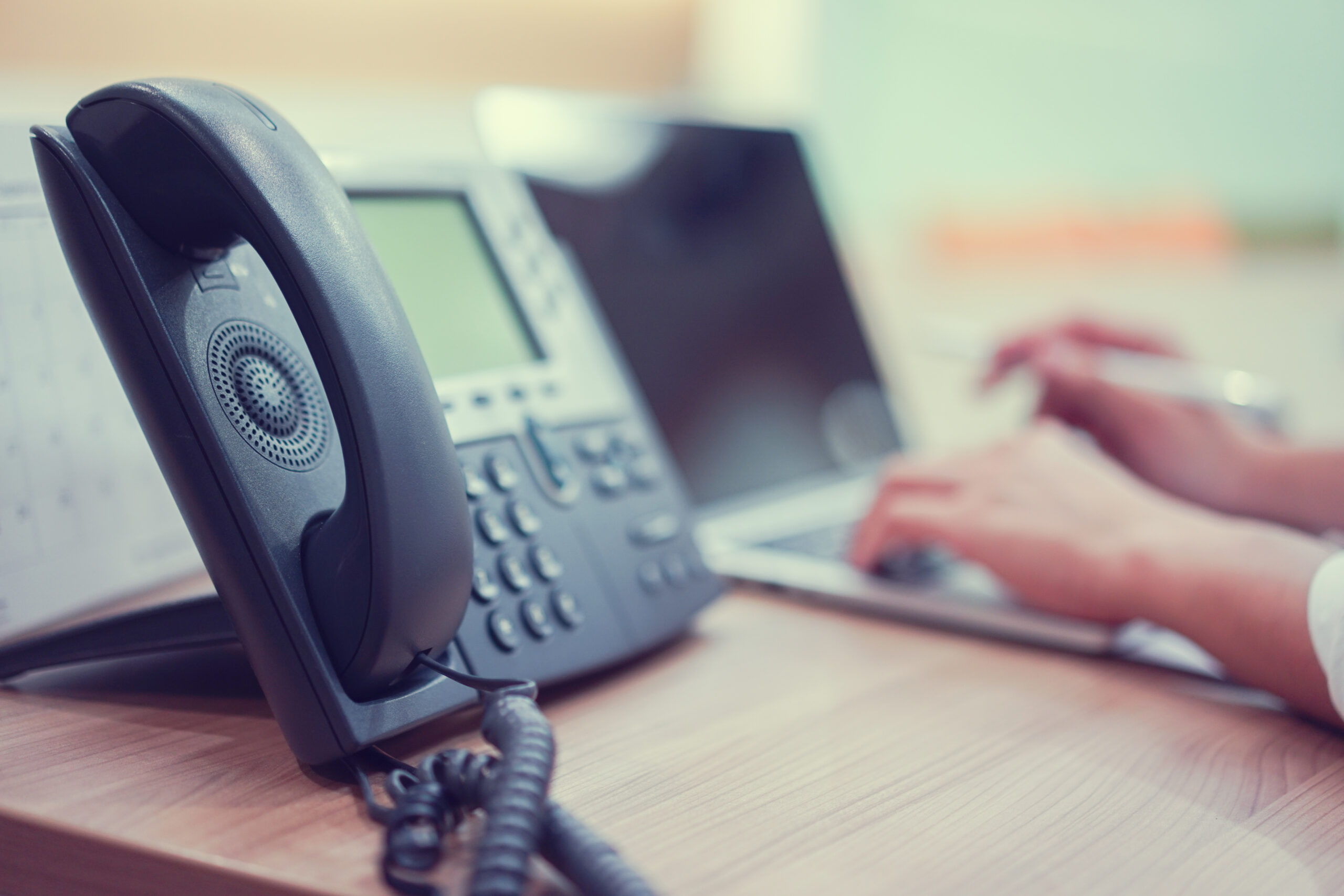 Close Up On Telephone With Employee Man Working On Laptop At Off
